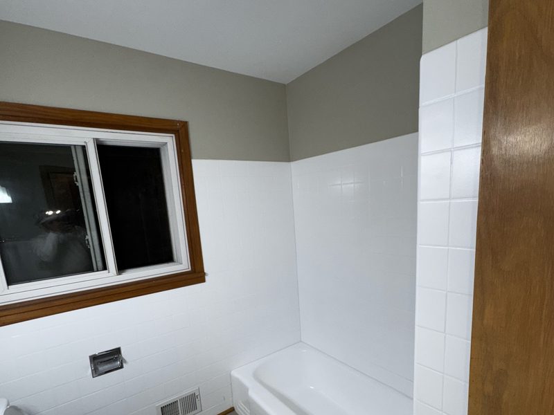 Completed bathroom with white tub, tile surround and vanity