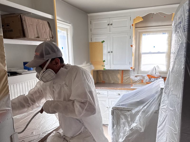 Cabinet refinishing in progress with surrounding surfaces masked