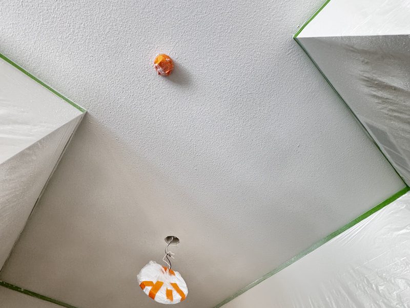 Finished white ceiling with painter's tape along the wall edges