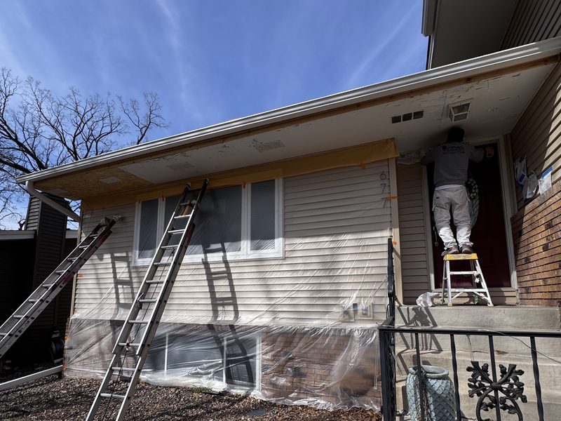 RYA painter working on exterior soffit and trim from a ladder