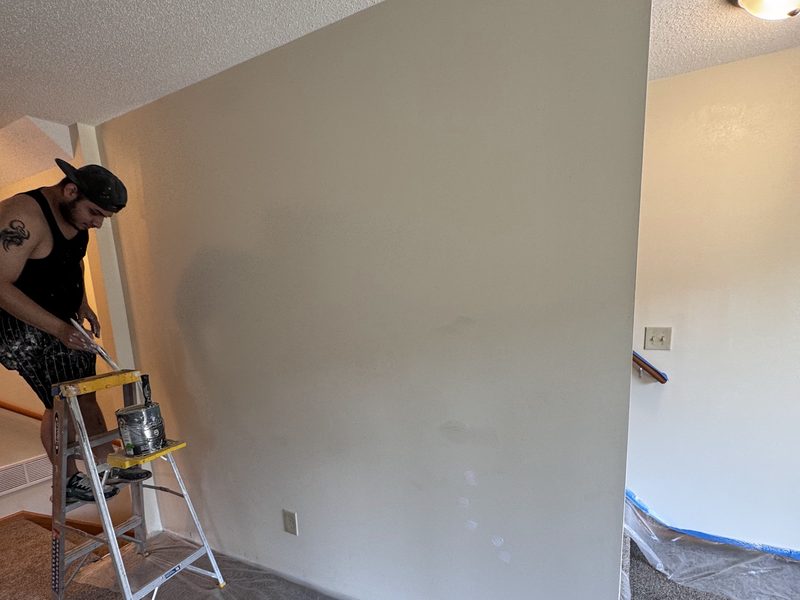Interior wall being painted above protective floor coverings