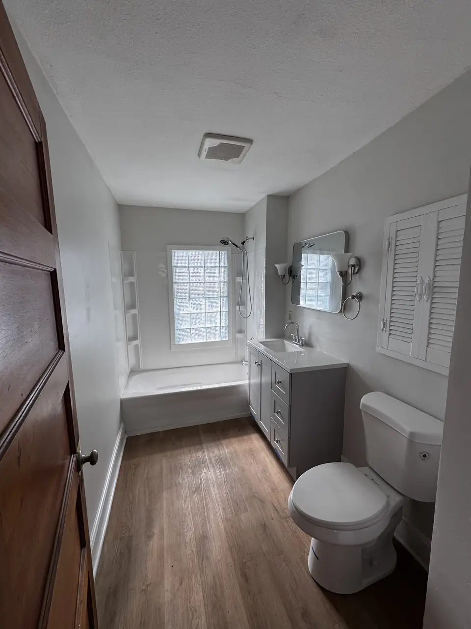Bathroom with a refinished gray vanity, quartz countertop and glass block window