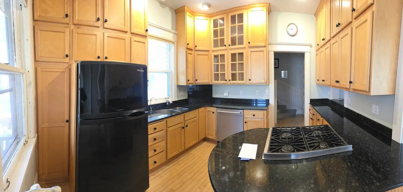 Kitchen with light wood cabinets, black appliances and a center island