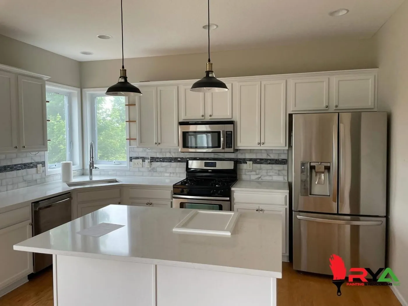 Finished kitchen with freshly painted white shaker cabinets, marble subway tile backsplash, and quartz counters after a cabinet refinishing project