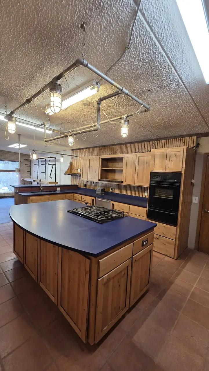 Kitchen island with blue countertop and knotty pine cabinetry
