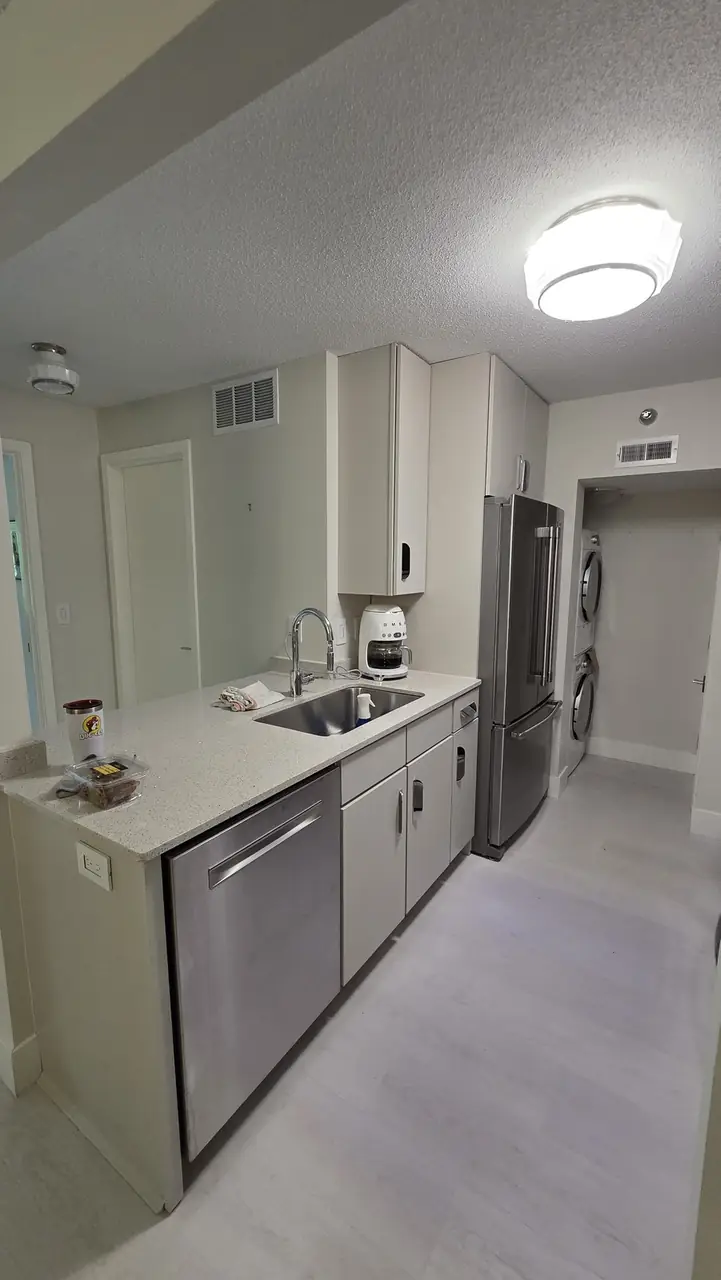 Kitchen with white cabinets, stainless appliances and a stacked washer and dryer