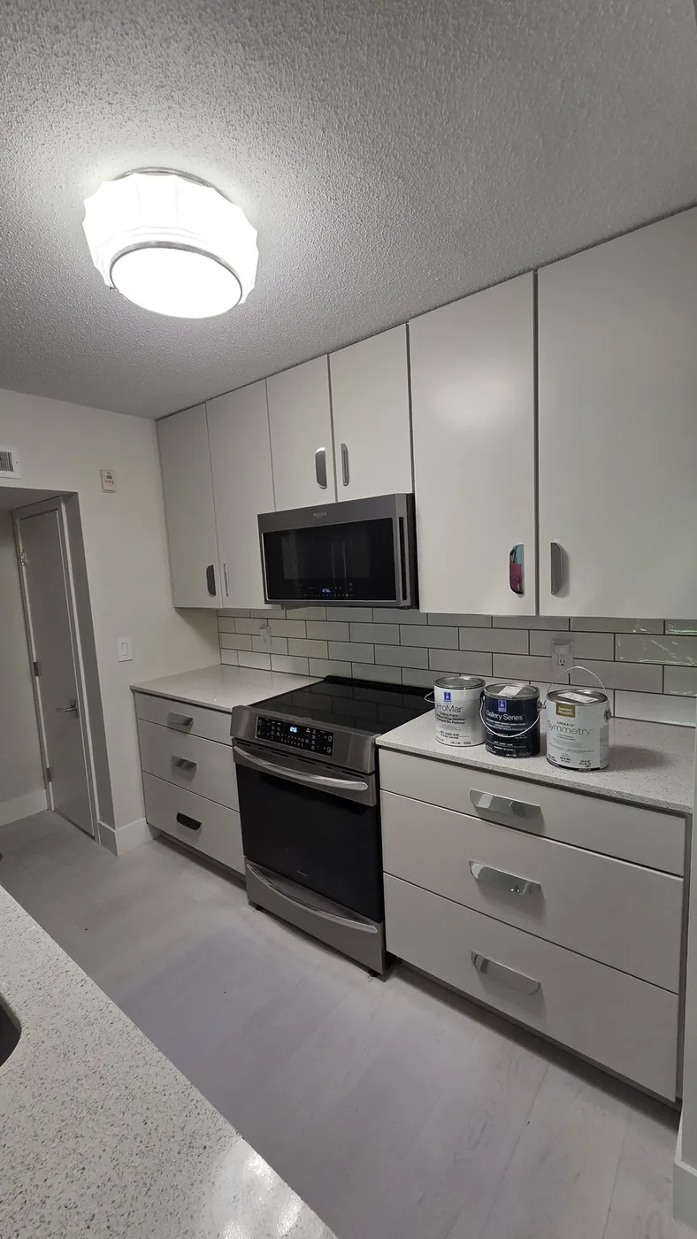 Cabinet refinishing job in progress, with cans of cabinet paint staged on the counter next to freshly painted cabinets