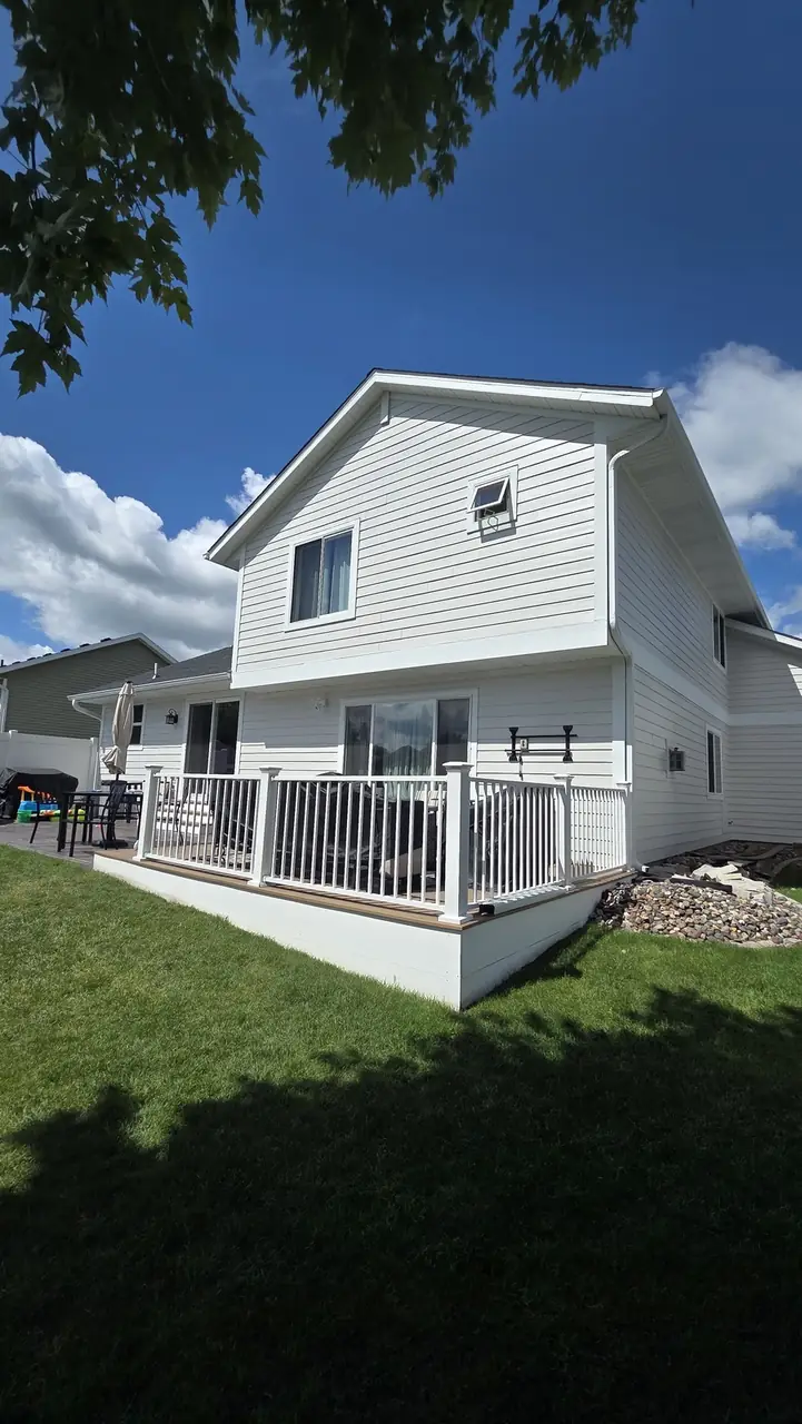 Two-story home exterior with a white deck, railing and a storage shed