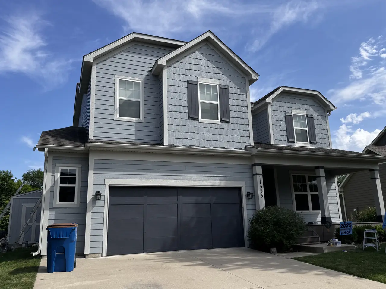 Two-story home exterior with gray siding, a navy garage door and covered front porch