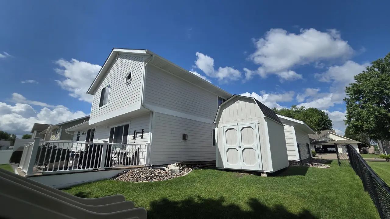 Two-story home exterior with white siding and a matching storage shed in the backyard
