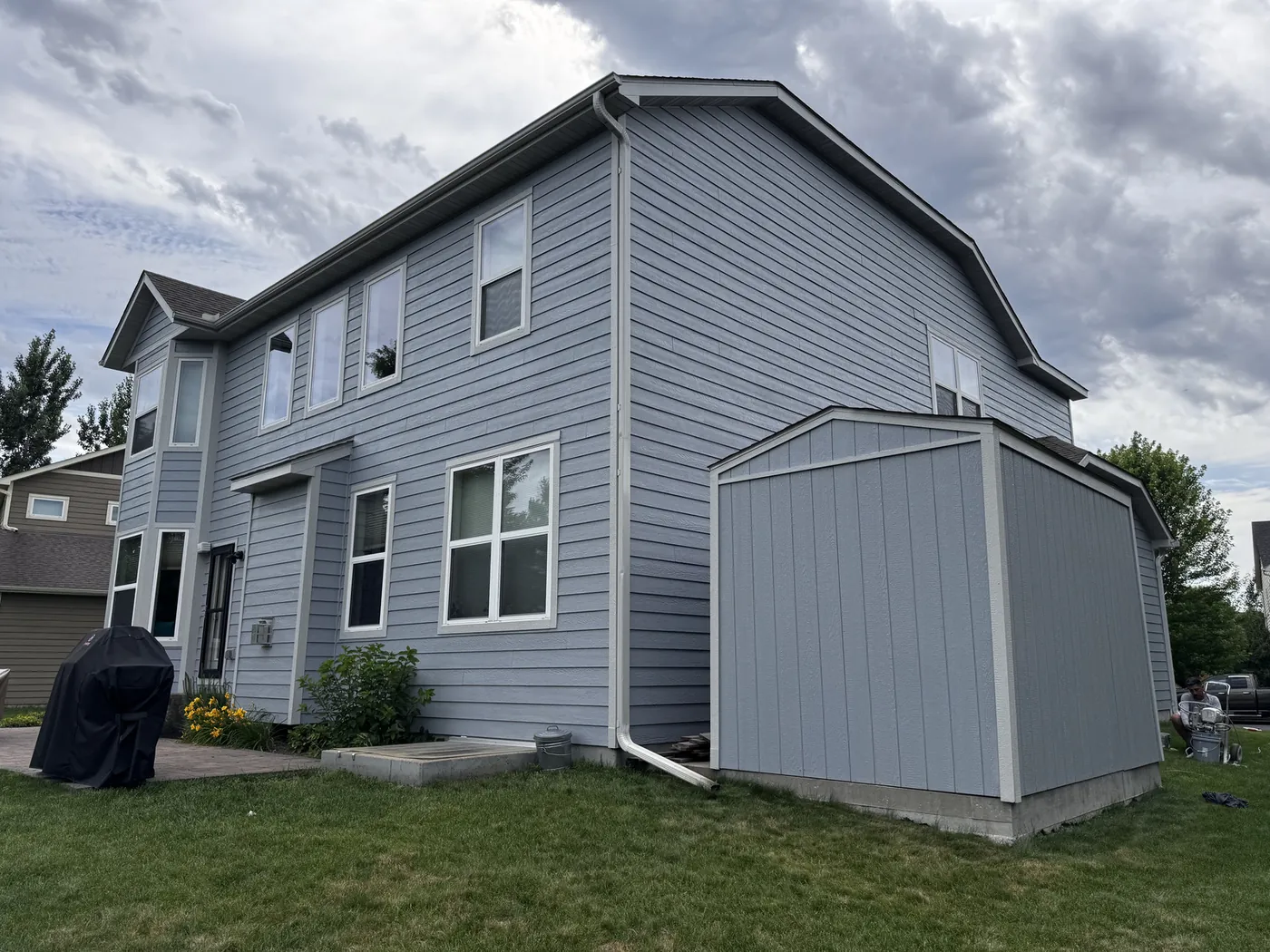 Two-story home with freshly painted blue-gray siding and a matching painted storage shed