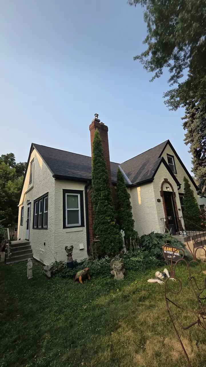 Tudor-style stucco home exterior with a brick chimney and arched entry door