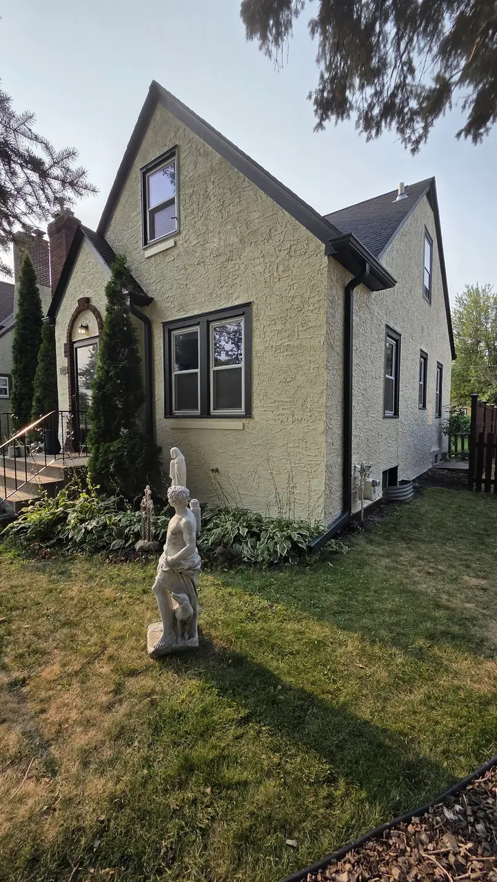 Side exterior of a stucco Tudor-style home with dormer windows
