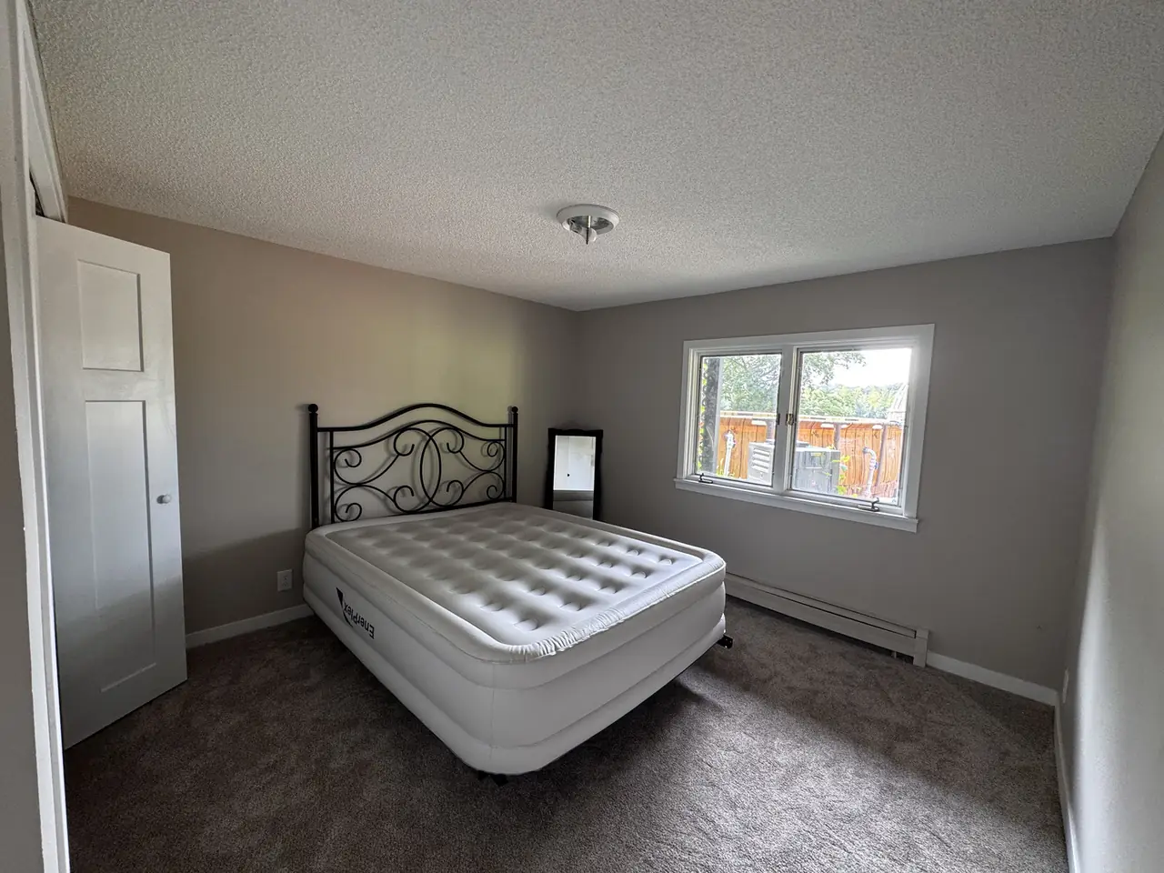 Furnished bedroom with freshly painted gray walls and a wrought iron bed frame