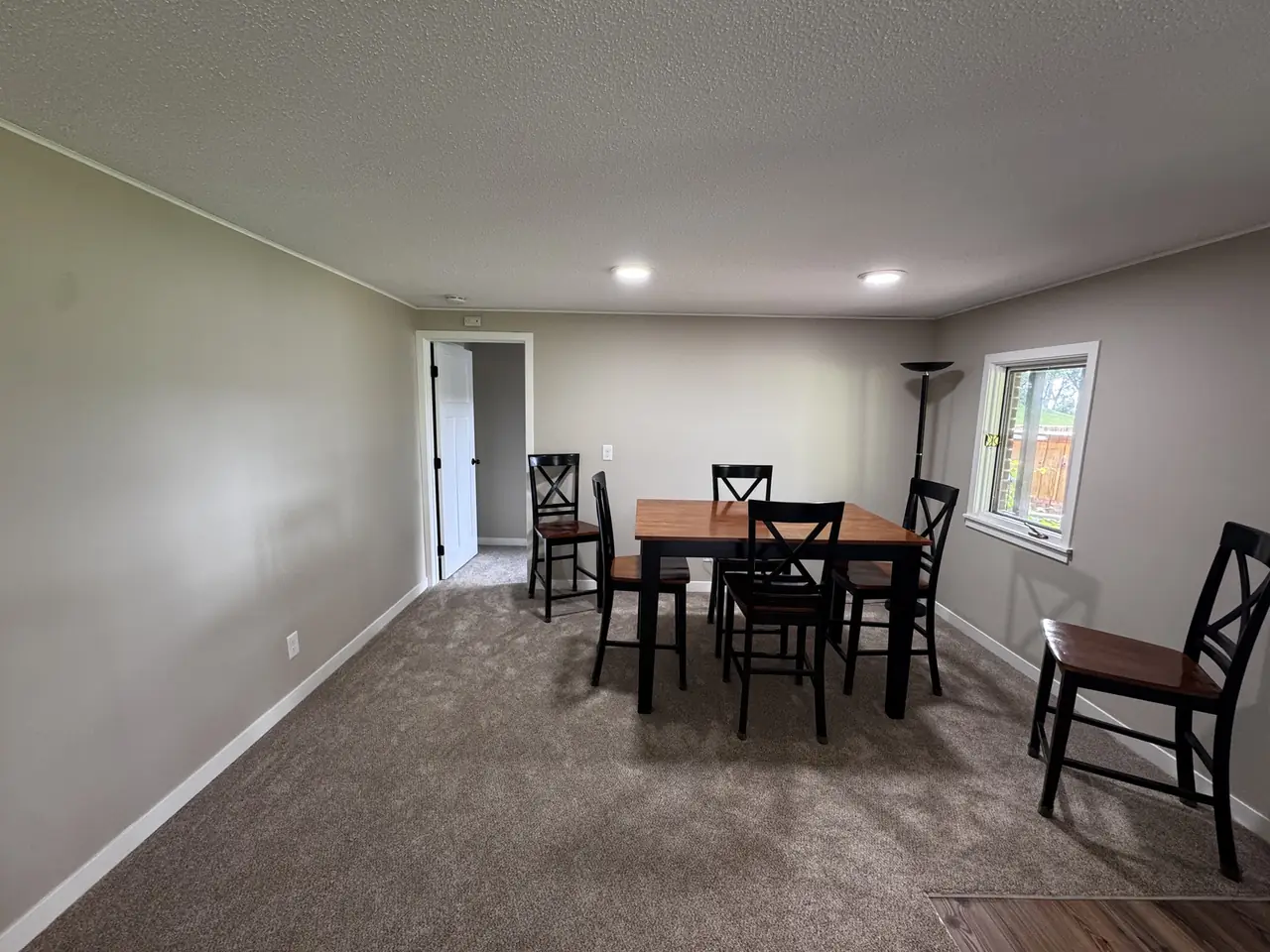 Furnished dining room with freshly painted tan walls and gray carpet