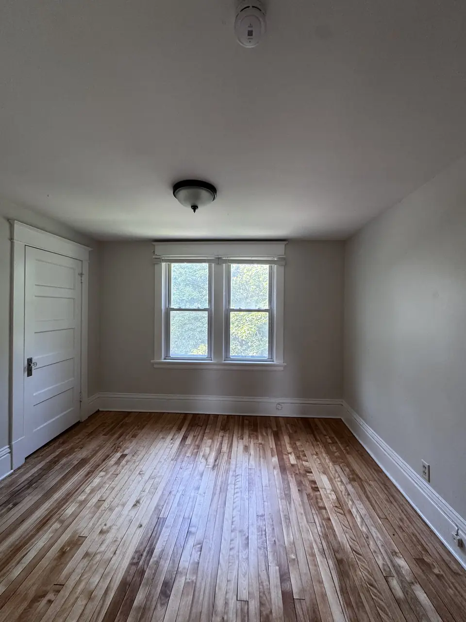 Empty bedroom with freshly painted white walls and a wood paneled door
