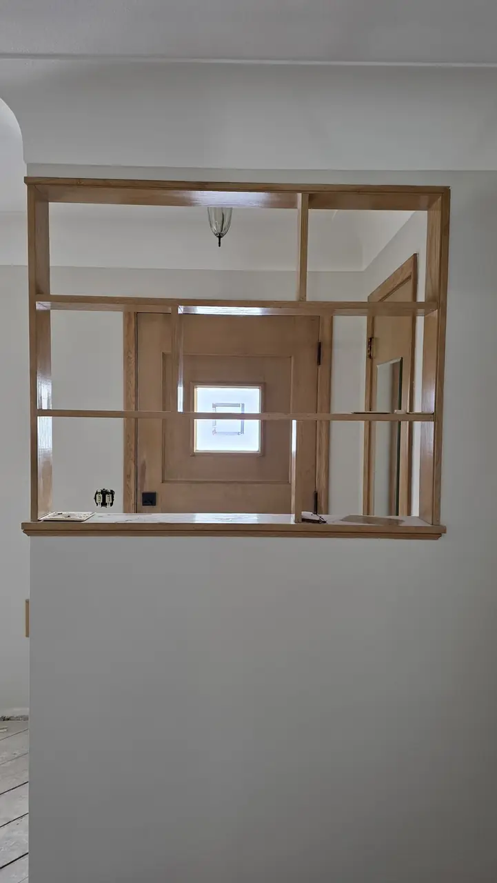 Built-in wood pass-through window and shelf between a kitchen and dining area