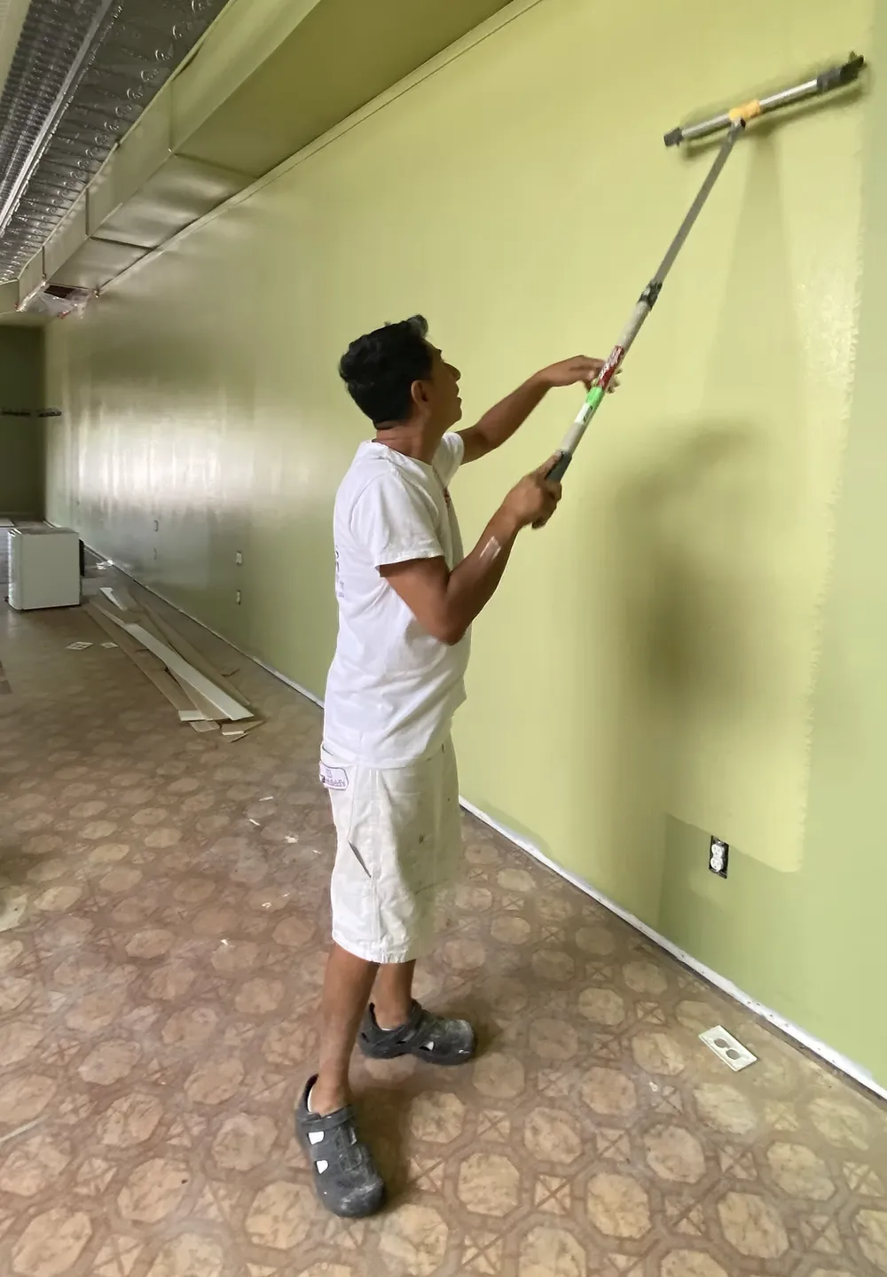 Painter rolling fresh light green paint onto a commercial interior wall