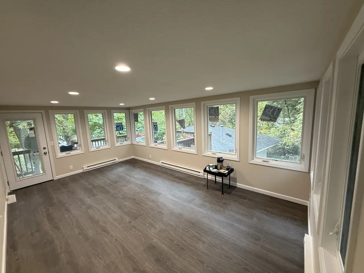 Freshly painted sunroom with a wall of windows overlooking a wooded backyard